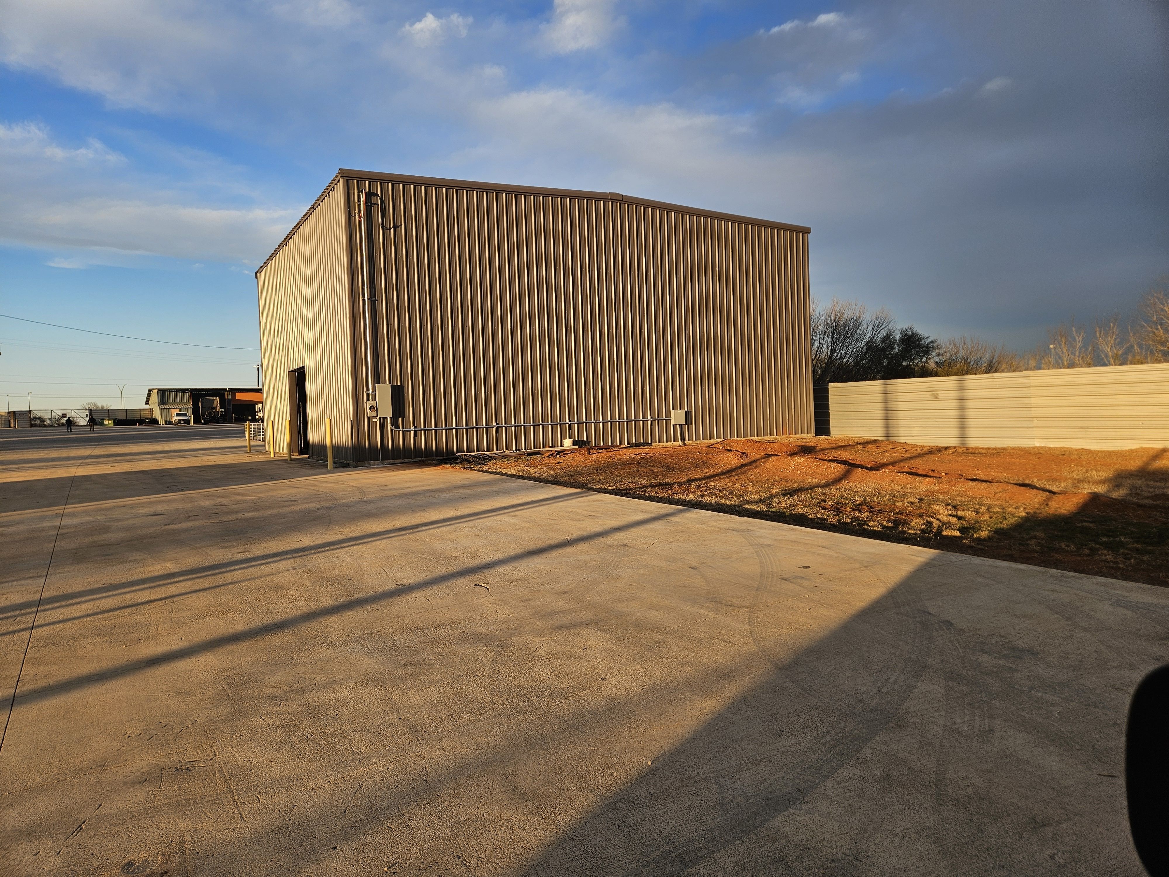 Metal commercial building with exterior conduit and disconnects at golden hour