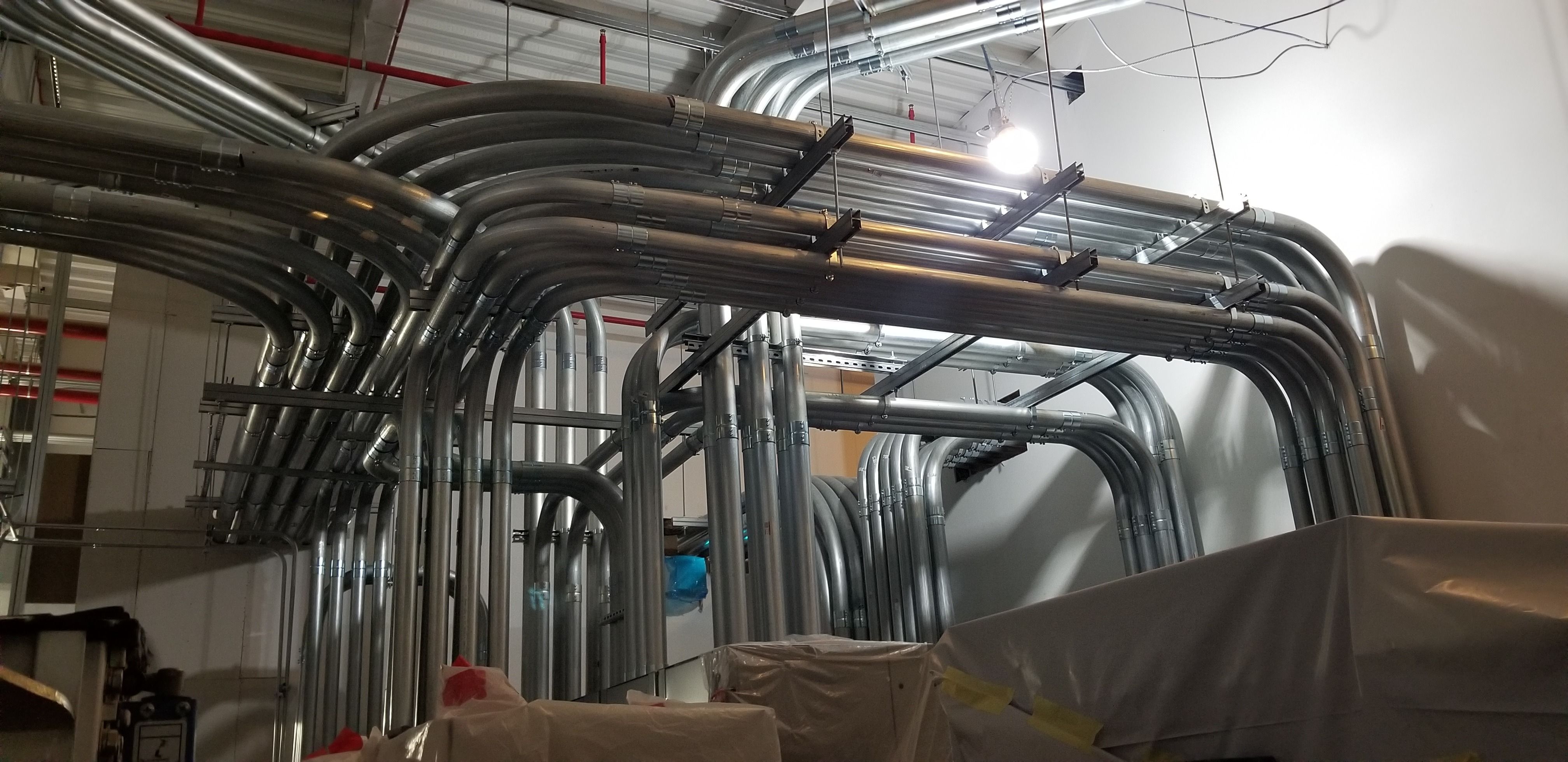 Multiple tiers of steel conduit turning together through a commercial space