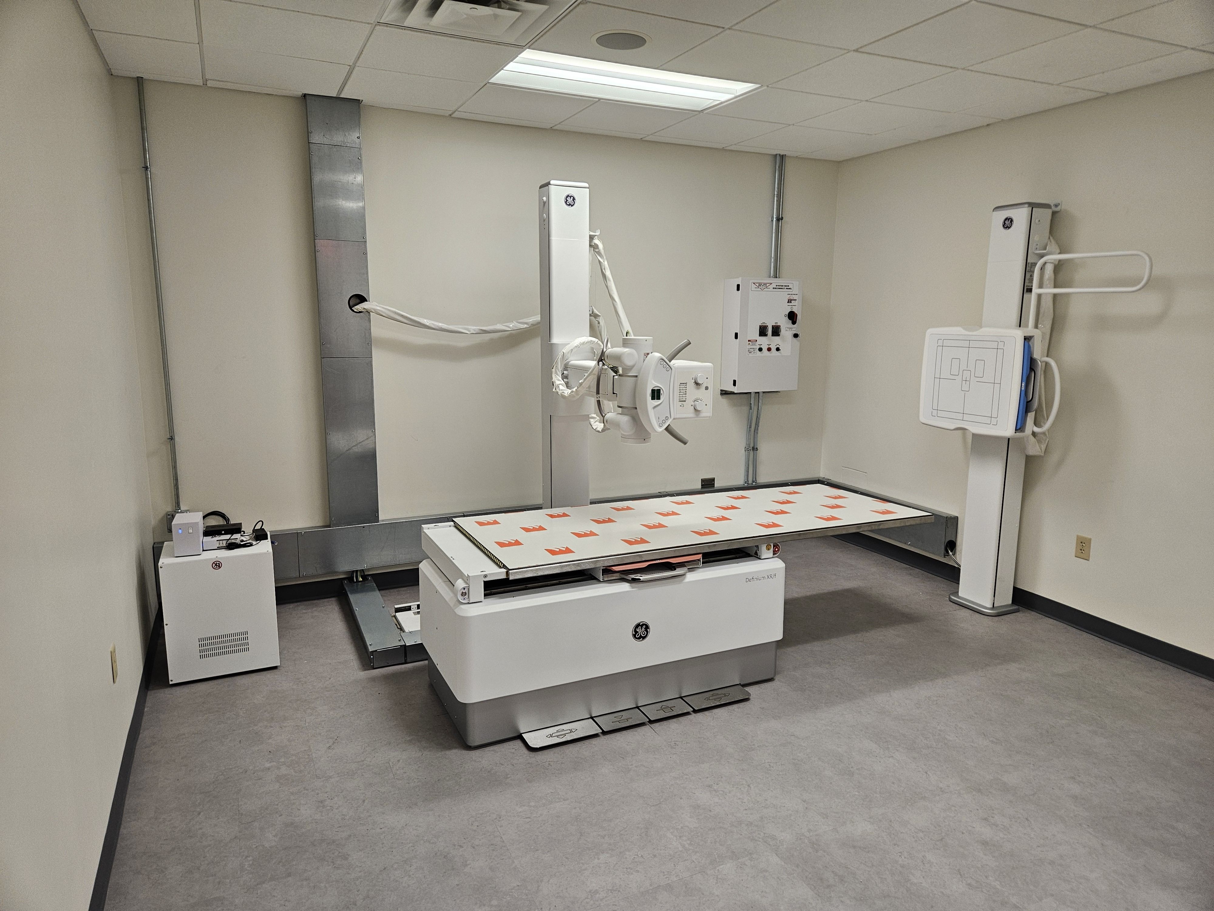 Imaging equipment room with a wall-mounted system main disconnect panel and conduit drops